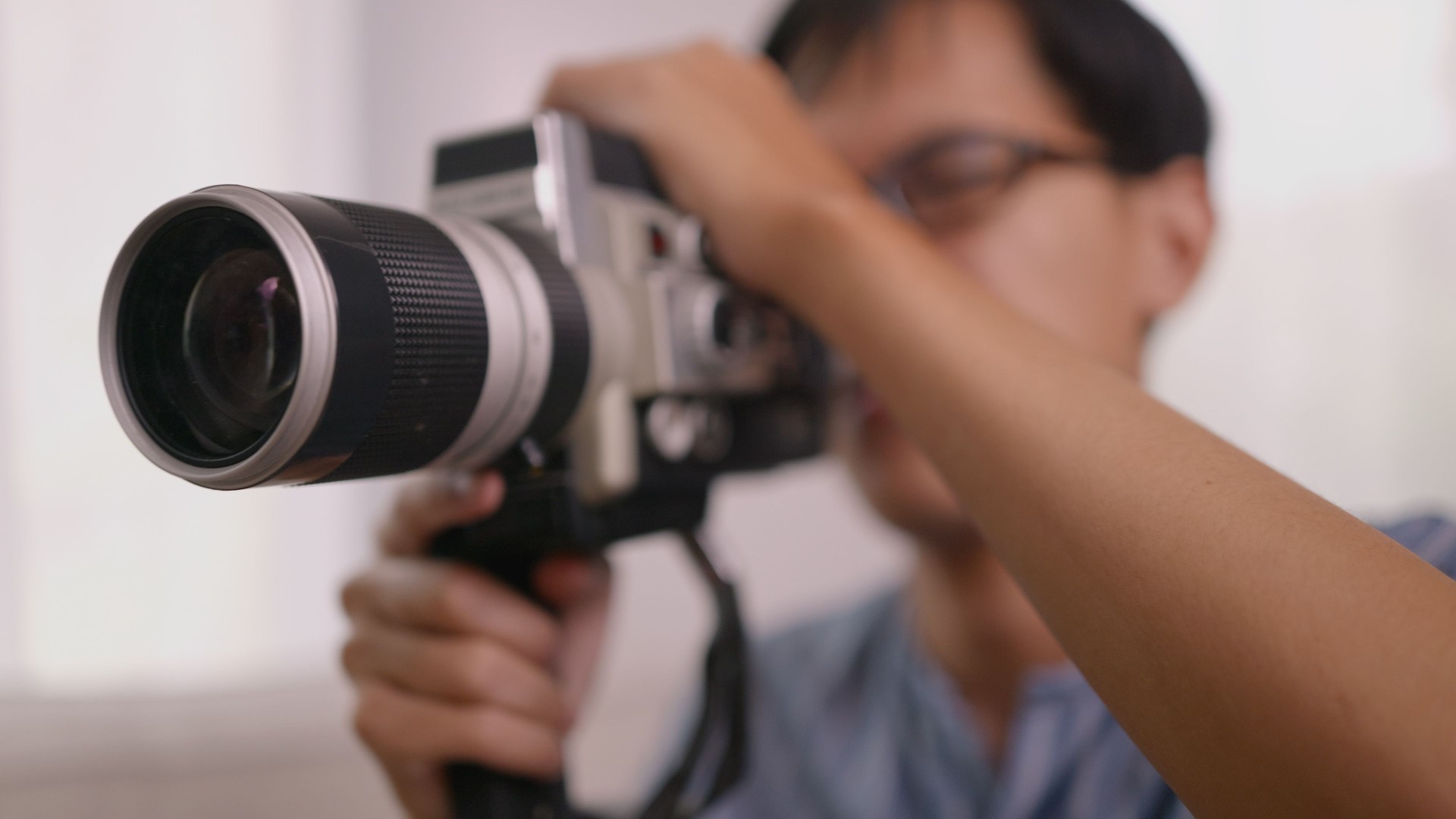 Asian Man Filming with Vintage Movie Camera – Retro Cinematic Style.